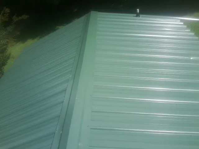 New green metal panels meeting at the ridge of a roof — Flat Roof Repair work by our crew in Spartansburg