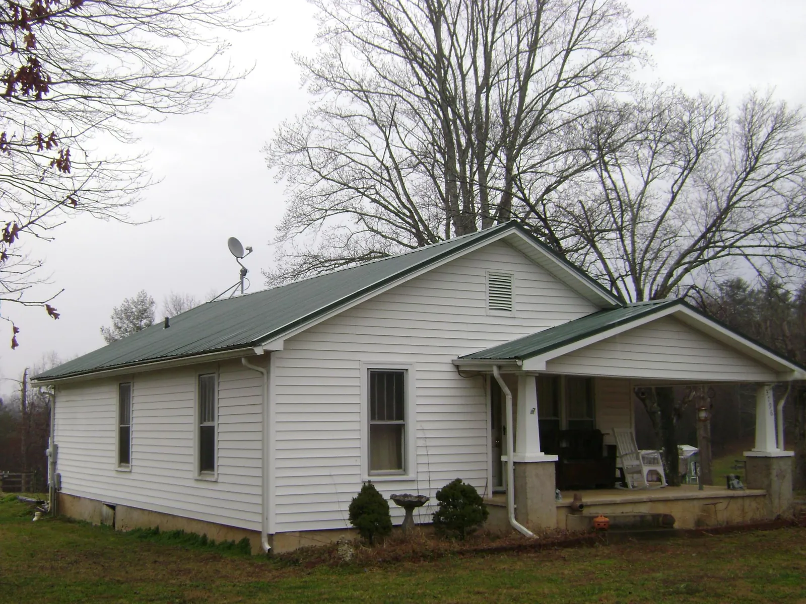 Green metal roof on a white bungalow with a side porch in Spartansburg