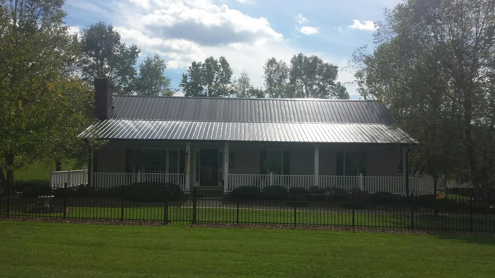 Gray metal roof on a brick ranch with a full width front porch — Gutter Guard Installation work by our crew in Spartansburg