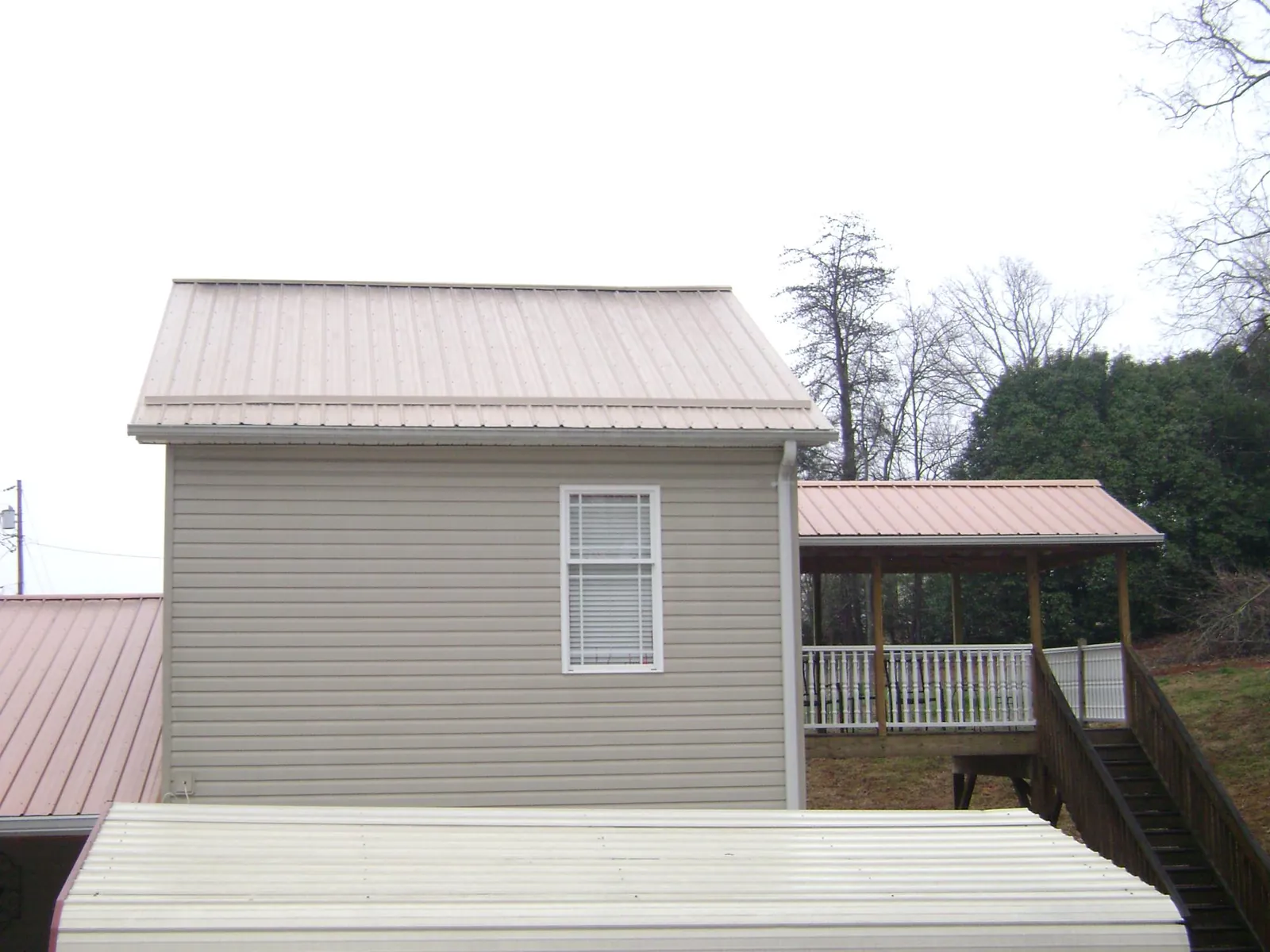 Tan metal roofs on a two story addition and attached porch, from a Roof Replacement job in Spartansburg