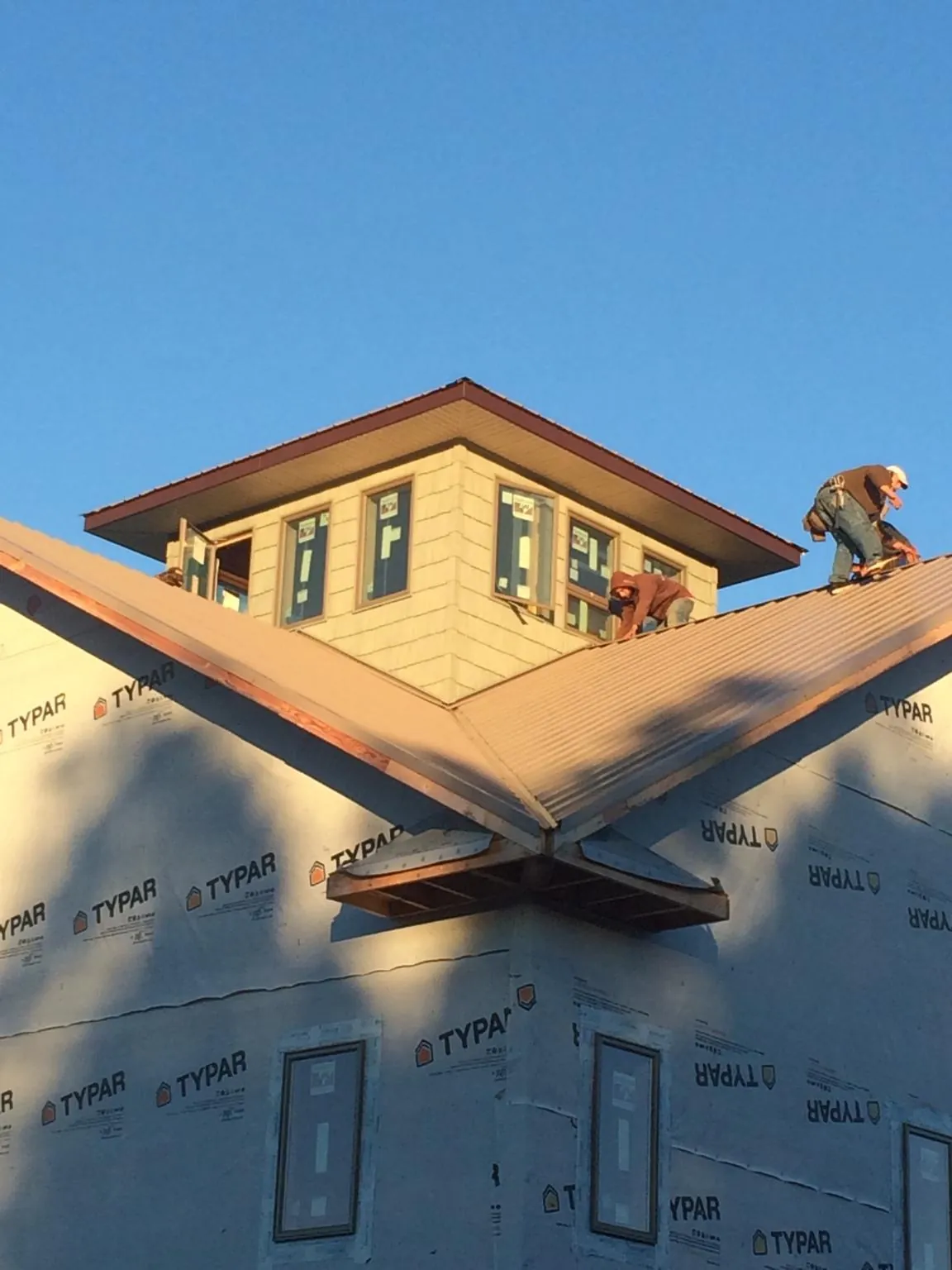 Roofers working around a rooftop cupola on a new metal roof at sunset — Roof Waterproofing in Spartansburg by Roofing Brothers